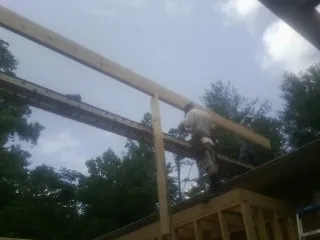 Carpenter setting a ridge beam over a new addition frame — Ice Dam Removal by Roofing Brothers in Bluewater