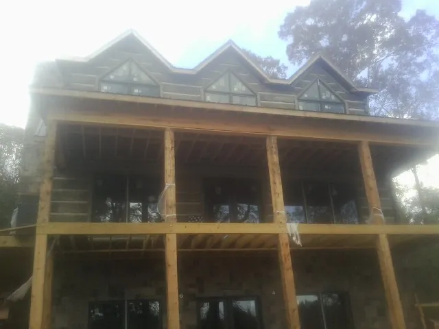 Dormers and porch framing on a large log home under construction — Roof Coating work by our crew in Bluewater