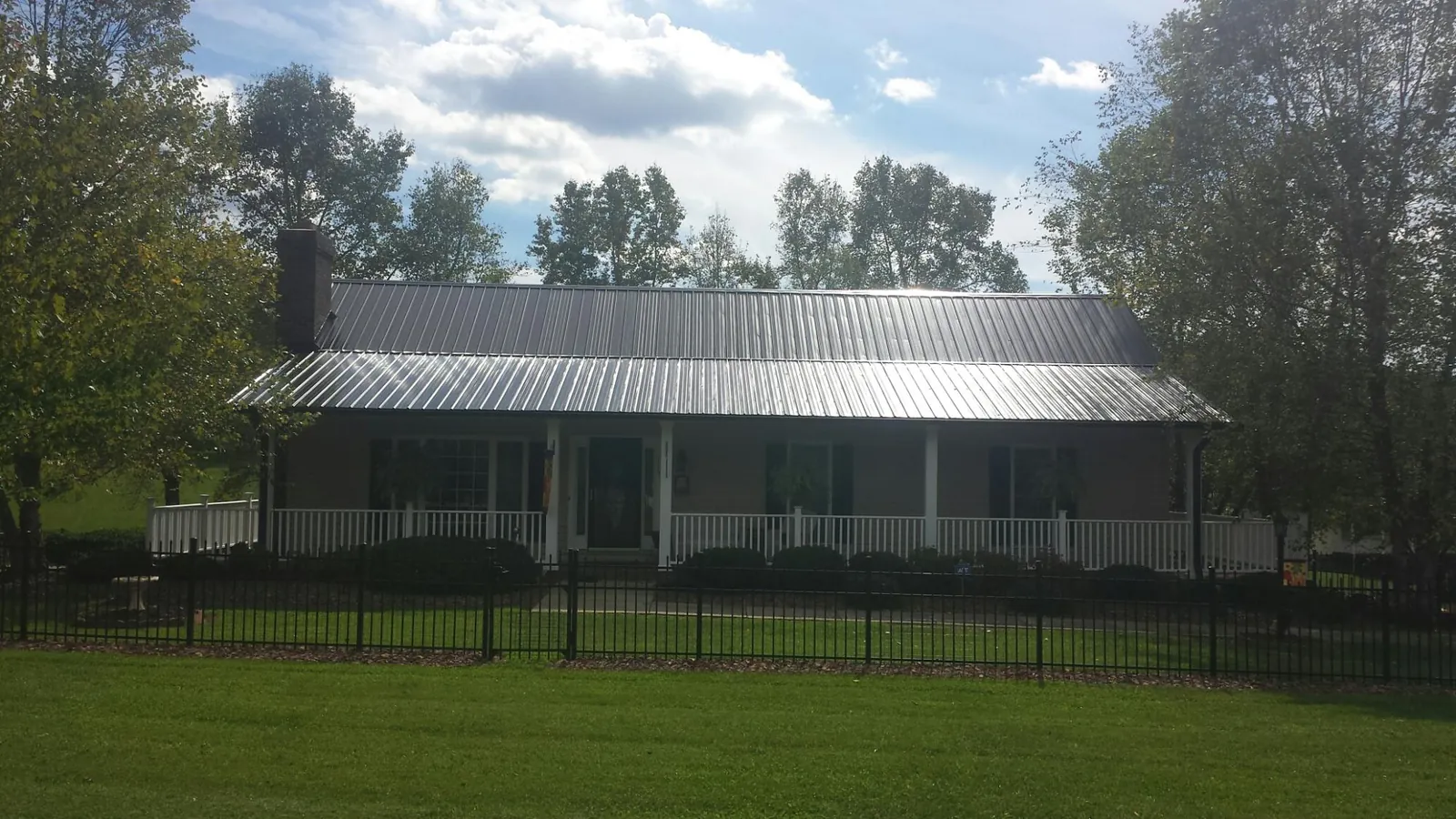 Gray metal roof on a brick ranch with a full width front porch — Gutter Guard Installation work by our crew in Bluewater